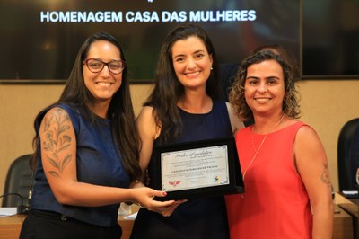 Cristiane Magalhães de Melo, coordenadora do projeto 'Casa de Mulheres', e Ana Flávia Soares Diniz, Defensora Pública, recebendo placa alusiva em homenagem aos 15 anos de trabalhos desenvolvidos pela organização