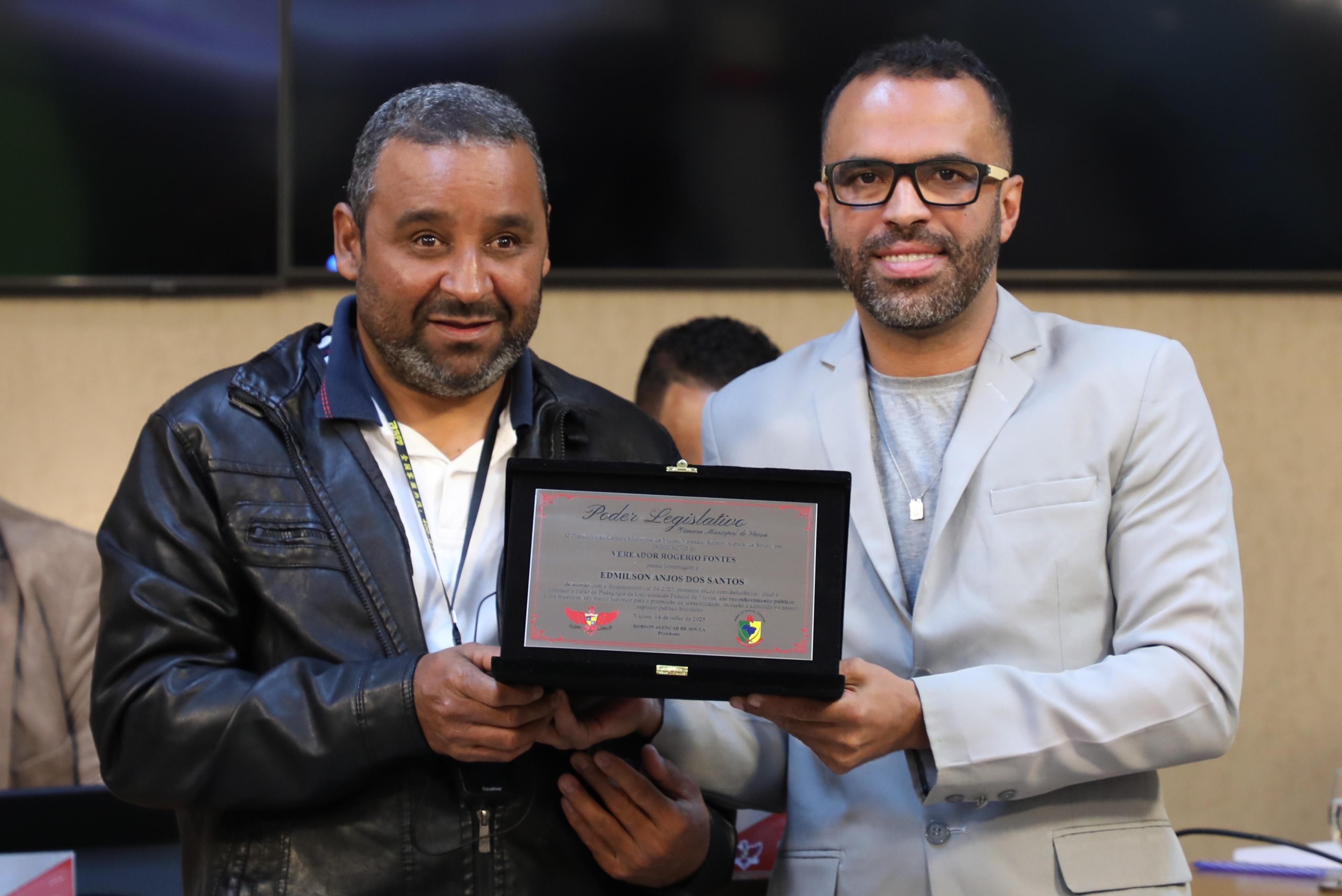 Entrega de Placa alusiva em homenagem a Edmilson Anjos dos Santos, primeiro aluno com deficiência visual a concluir o curso de Pedagogia da Universidade Federal de Viçosa, destacando sua trajetória, que não representa apenas uma conquista pessoal, mas também um marco histórico para a promoção da acessibilidade, inclusão e equidade no ensino superior público brasileiro