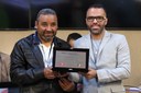 Entrega de Placa alusiva em homenagem a Edmilson Anjos dos Santos, primeiro aluno com deficiência visual a concluir o curso de Pedagogia da Universidade Federal de Viçosa, destacando sua trajetória, que não representa apenas uma conquista pessoal, mas também um marco histórico para a promoção da acessibilidade, inclusão e equidade no ensino superior público brasileiro